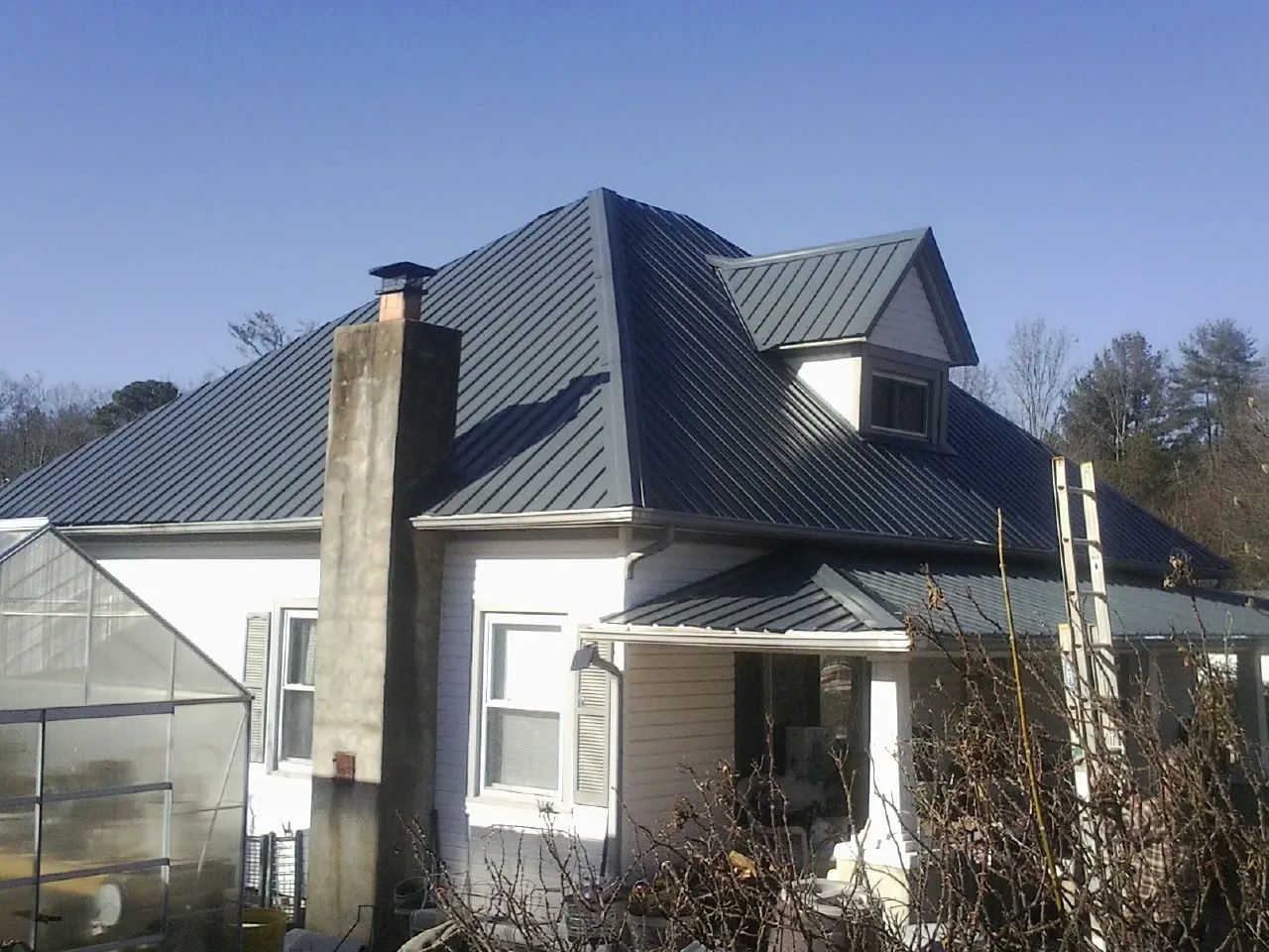 Dark blue standing seam metal roof on a white farmhouse with dormer — Slate & Tile Roof Repair by Roofing Brothers in Hayfork