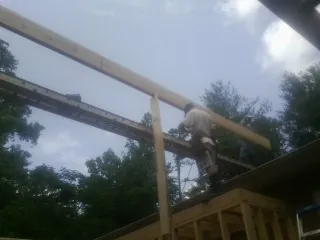 Carpenter setting a ridge beam over a new addition frame — Ice Dam Removal by Roofing Brothers in Hayfork