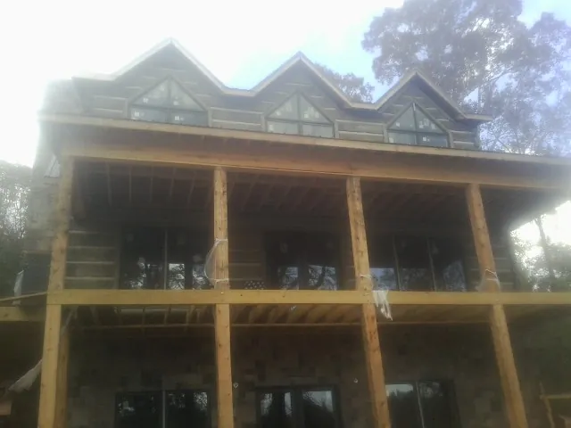 Dormers and porch framing on a large log home under construction — Roof Coating work by our crew in Hayfork