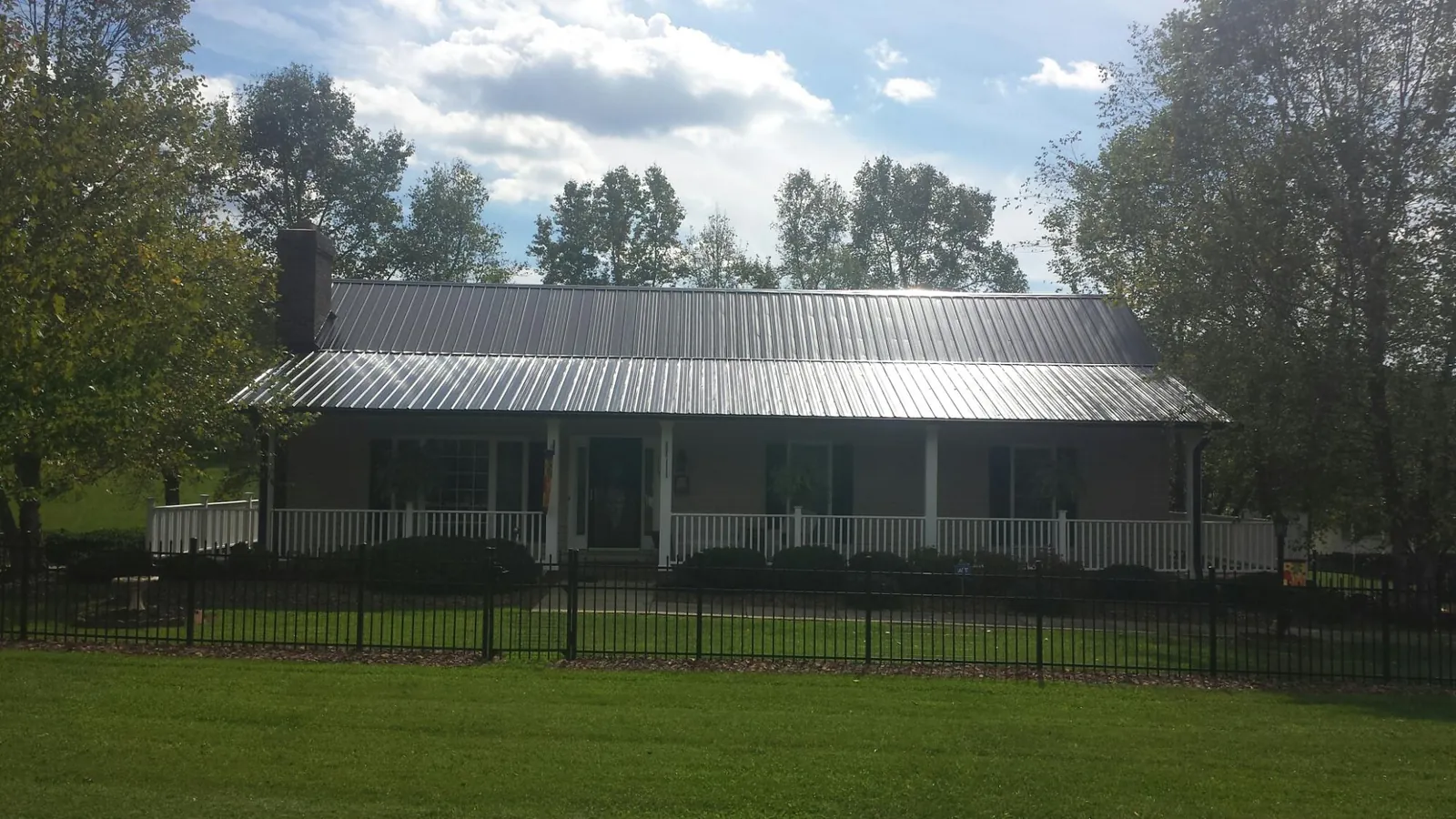 Gray metal roof on a brick ranch with a full width front porch — Gutter Guard Installation work by our crew in Hayfork