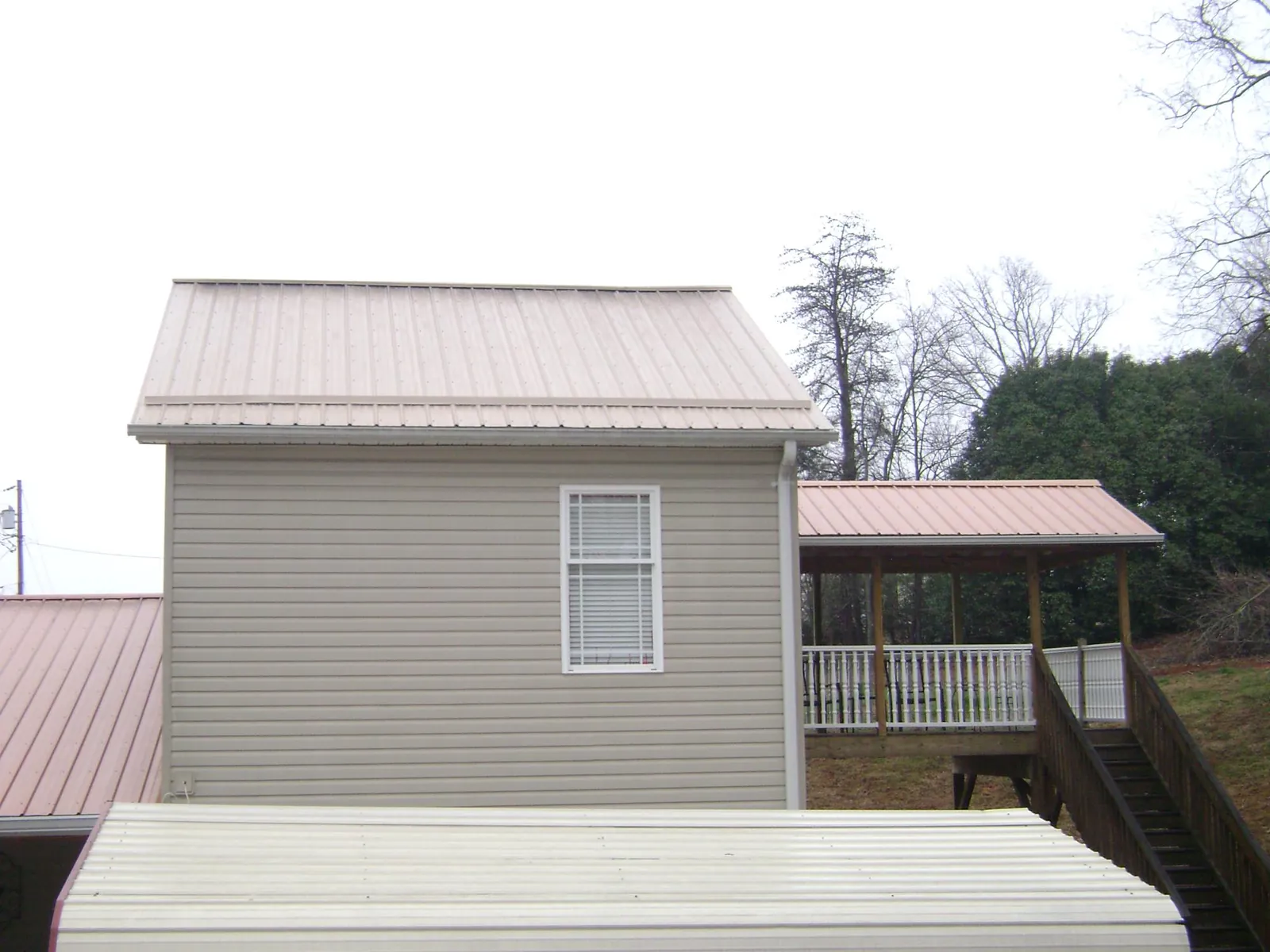Tan metal roofs on a two story addition and attached porch, from a Roof Replacement job in Hayfork