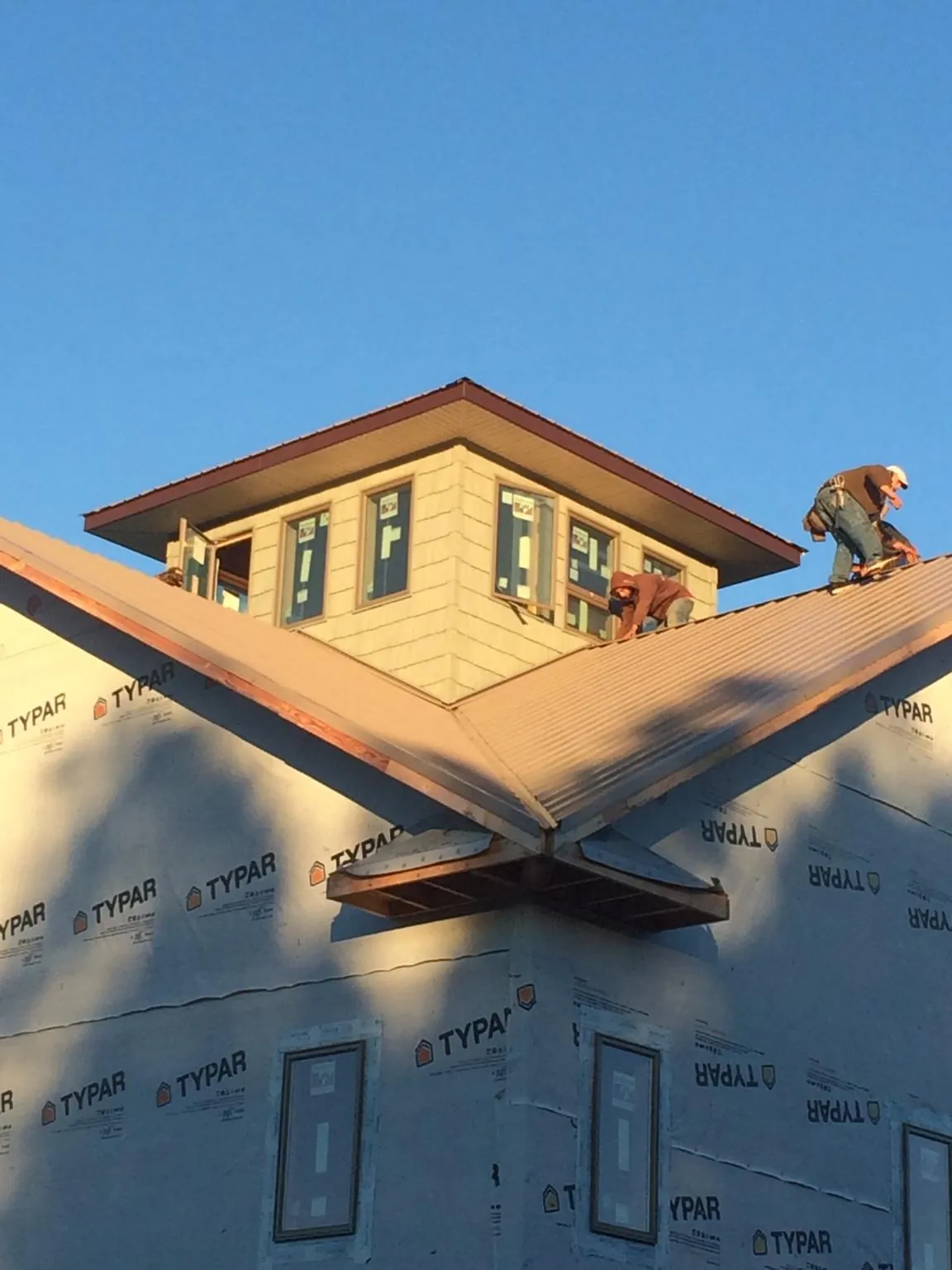 Roofers working around a rooftop cupola on a new metal roof at sunset — Roof Waterproofing in Hayfork by Roofing Brothers